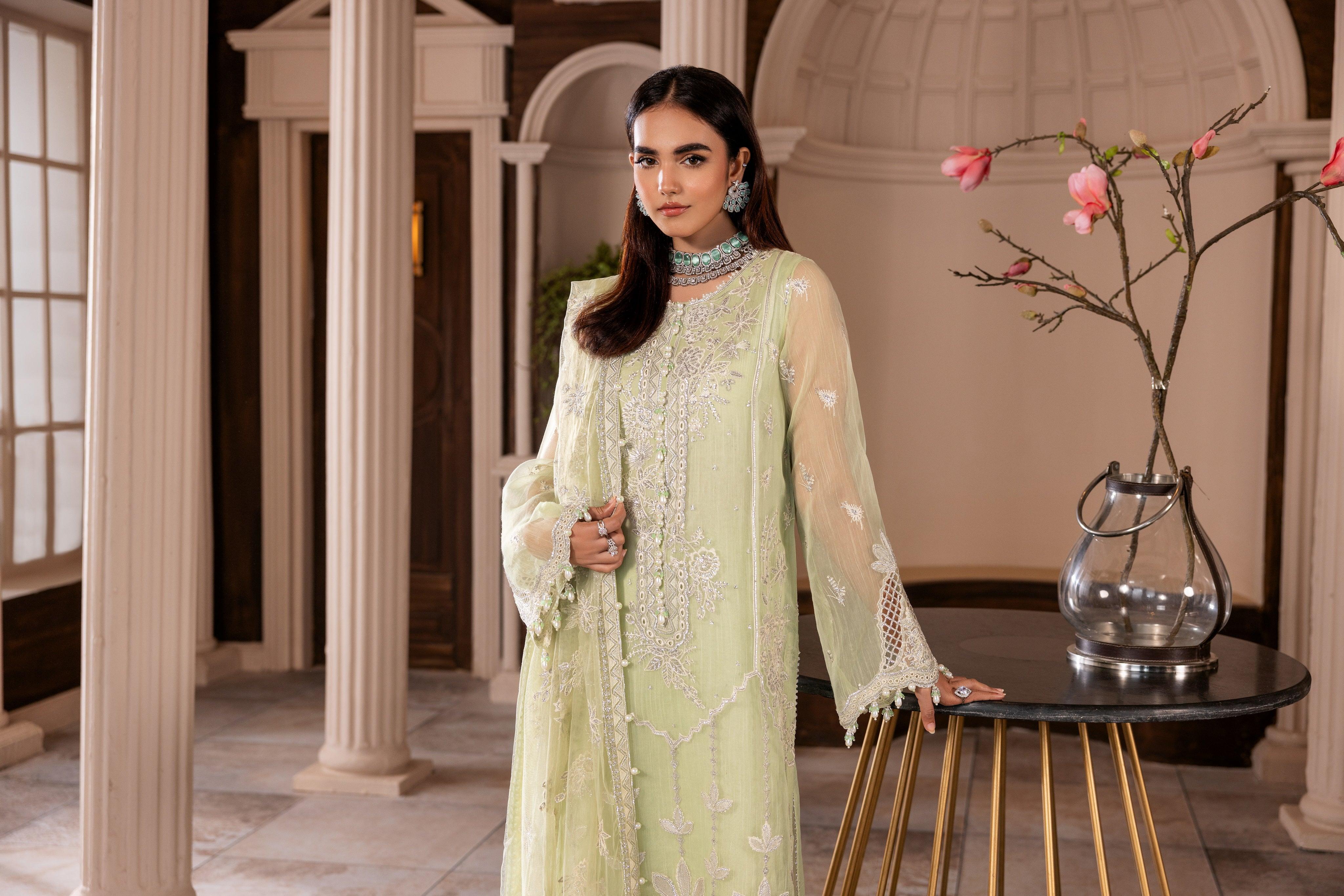 Woman in embroidered pastel green dress at LA ELISE, standing indoors near floral decor