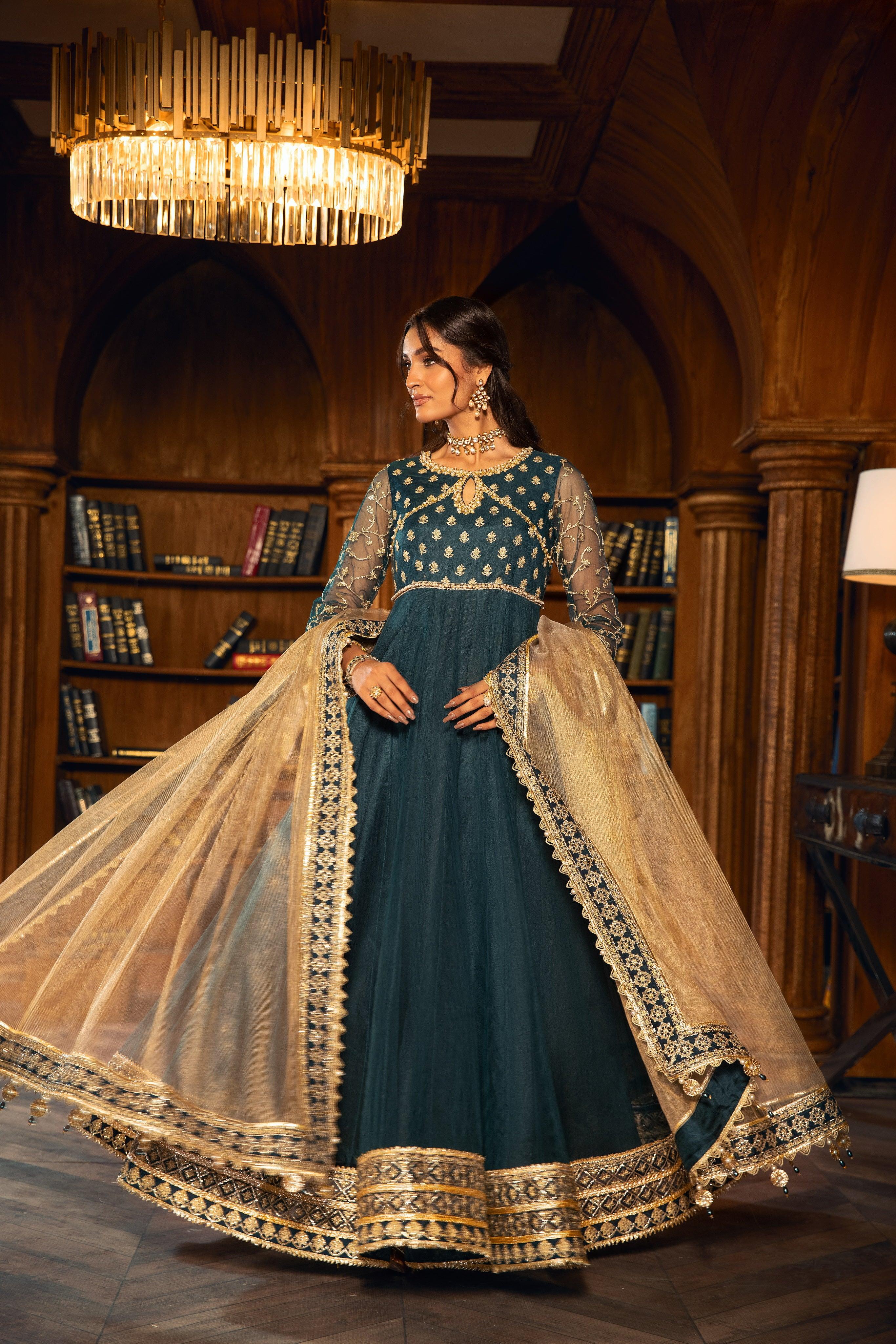 Woman wearing an elegant teal and gold formal dress from LA ELISE in a luxury library