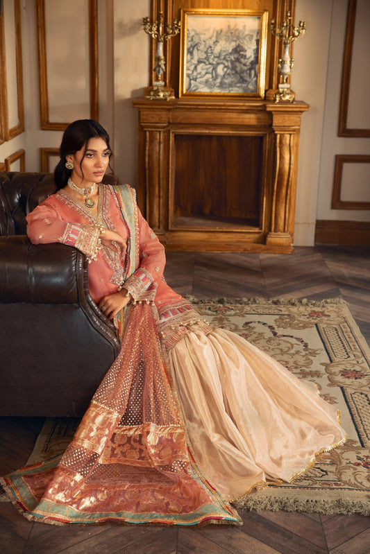 Woman in traditional peach and gold embroidered formal dress from LA ELISE sitting indoors