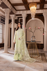 Elegant woman in pastel green embroidered formal dress from LA ELISE standing in a classic interior with columns and chandelier.