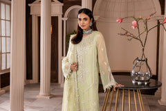 Woman in embroidered pastel green dress at LA ELISE, standing indoors near floral decor