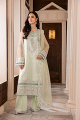 Woman wearing pastel green embroidered formal dress from LA ELISE, standing in a hallway