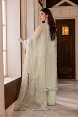Woman in pastel green embellished unstitched suit by LA ELISE, standing by window indoors