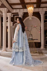 Woman in elegant pastel blue embroidered formal dress by LA ELISE, posing in a grand interior with classical columns.
