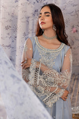 Woman in elegant blue embroidered formal dress from LA ELISE, posing with floral background