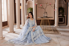 Woman in pastel blue formal dress with silver embroidery seated in elegant room at LA ELISE
