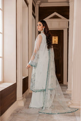 Woman in elegant light blue embroidered formal suit at LA ELISE, standing in a classic hallway