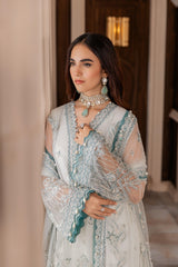 Woman in pastel embroidered formal dress with statement jewelry at LA ELISE fashion store