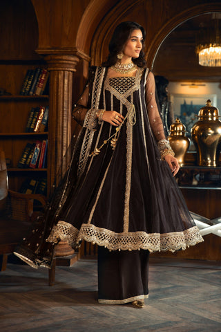 Woman in black and gold formal festive dress from LA ELISE, standing in a luxe library setting