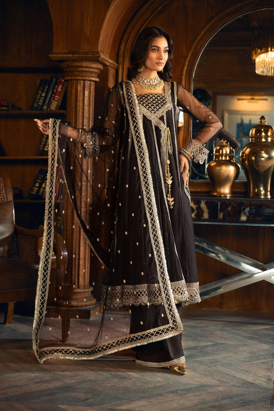 Woman in black and gold embroidered formal dress from LA ELISE, standing in elegant room