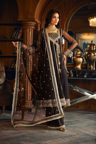 Woman in black and gold embroidered formal dress from LA ELISE, standing in elegant room