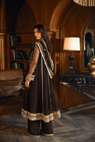 Woman in elegant black embroidered formal dress by LA ELISE, standing in a wood-paneled room