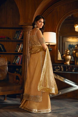 Elegant woman in gold embellished formal dress from LA ELISE, standing in a stylish, wood-paneled room