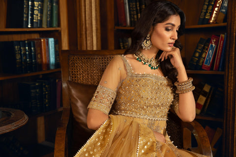 Woman in gold embroidered formal dress and jewelry sitting in library, LA ELISE fashion