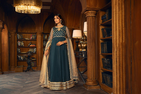 Woman in elegant teal and gold formal dress from LA ELISE, posing in luxe library setting