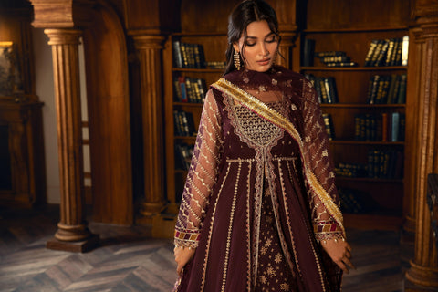 Woman in maroon embroidered formal dress from LA ELISE, standing in an elegant library