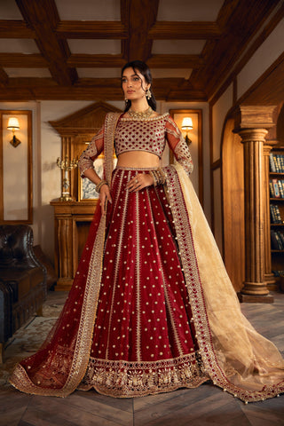 Woman in a maroon embroidered formal lehenga with gold dupatta in elegant room, LA ELISE fashion