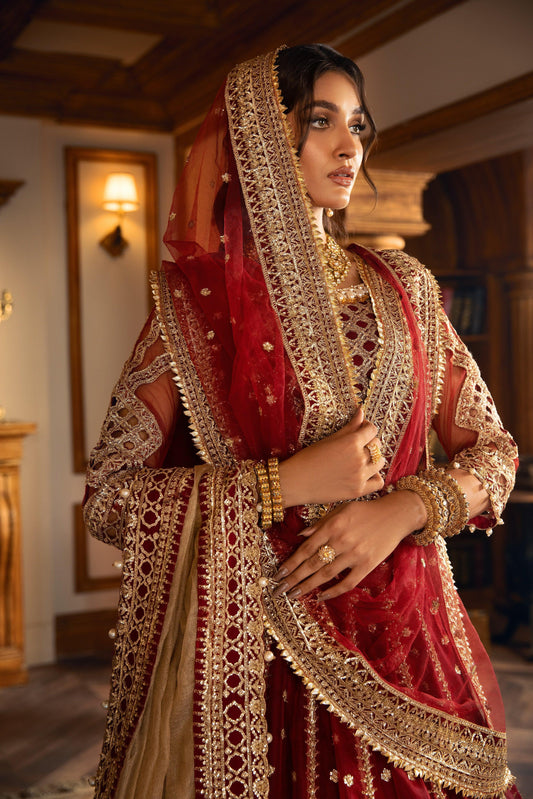 Woman in ornate maroon and gold formal dress with intricate embroidery at LA ELISE