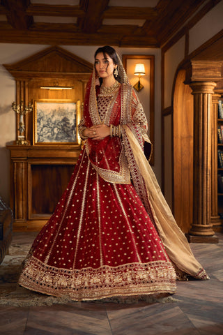 Woman in elegant red and gold embroidered formal dress by LA ELISE, standing indoors.